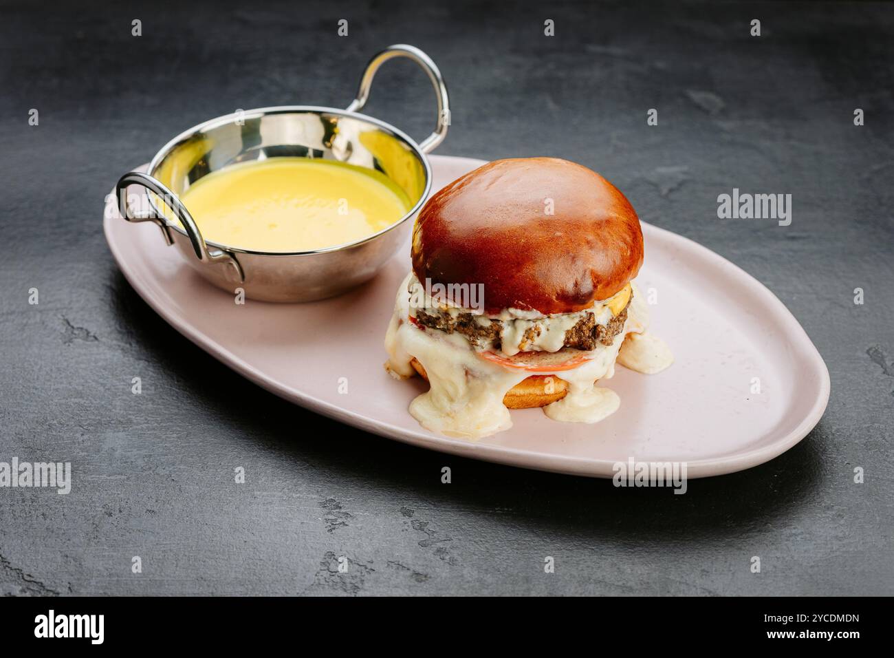 Hamburger juteux avec fromage fondu, tomate et sauce crémeuse pour une expérience culinaire ultime Banque D'Images