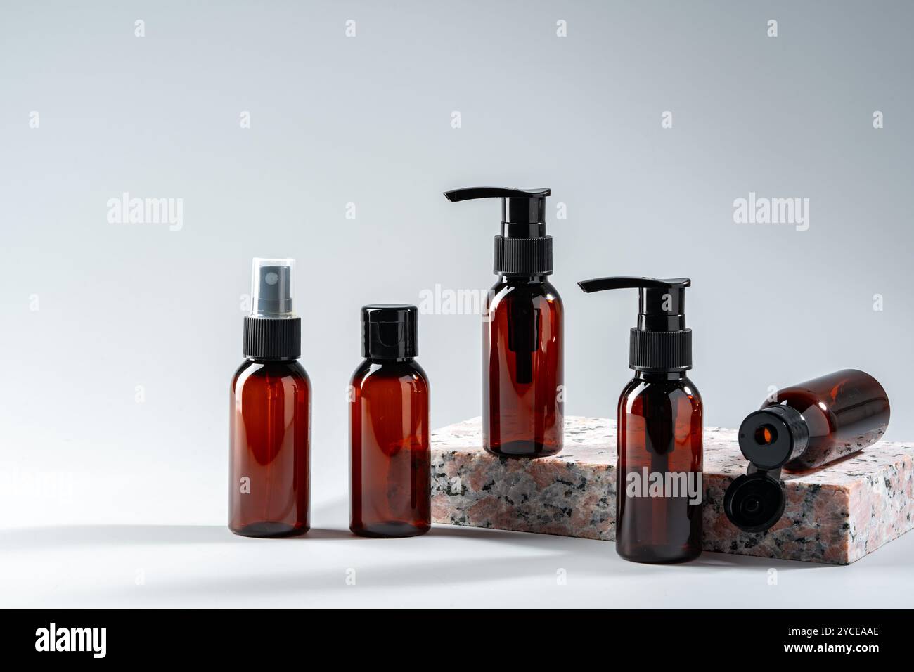 Élégantes bouteilles en verre ambré exposées sur une surface en pierre texturée dans un cadre de studio minimaliste Banque D'Images