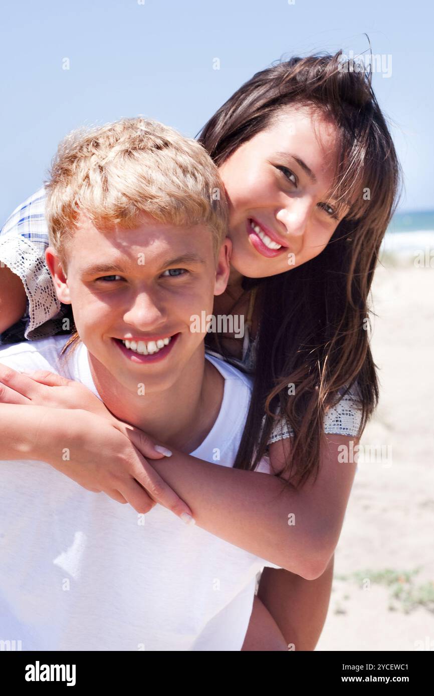 Girl riding sur guy de beach and smiling at camera Banque D'Images