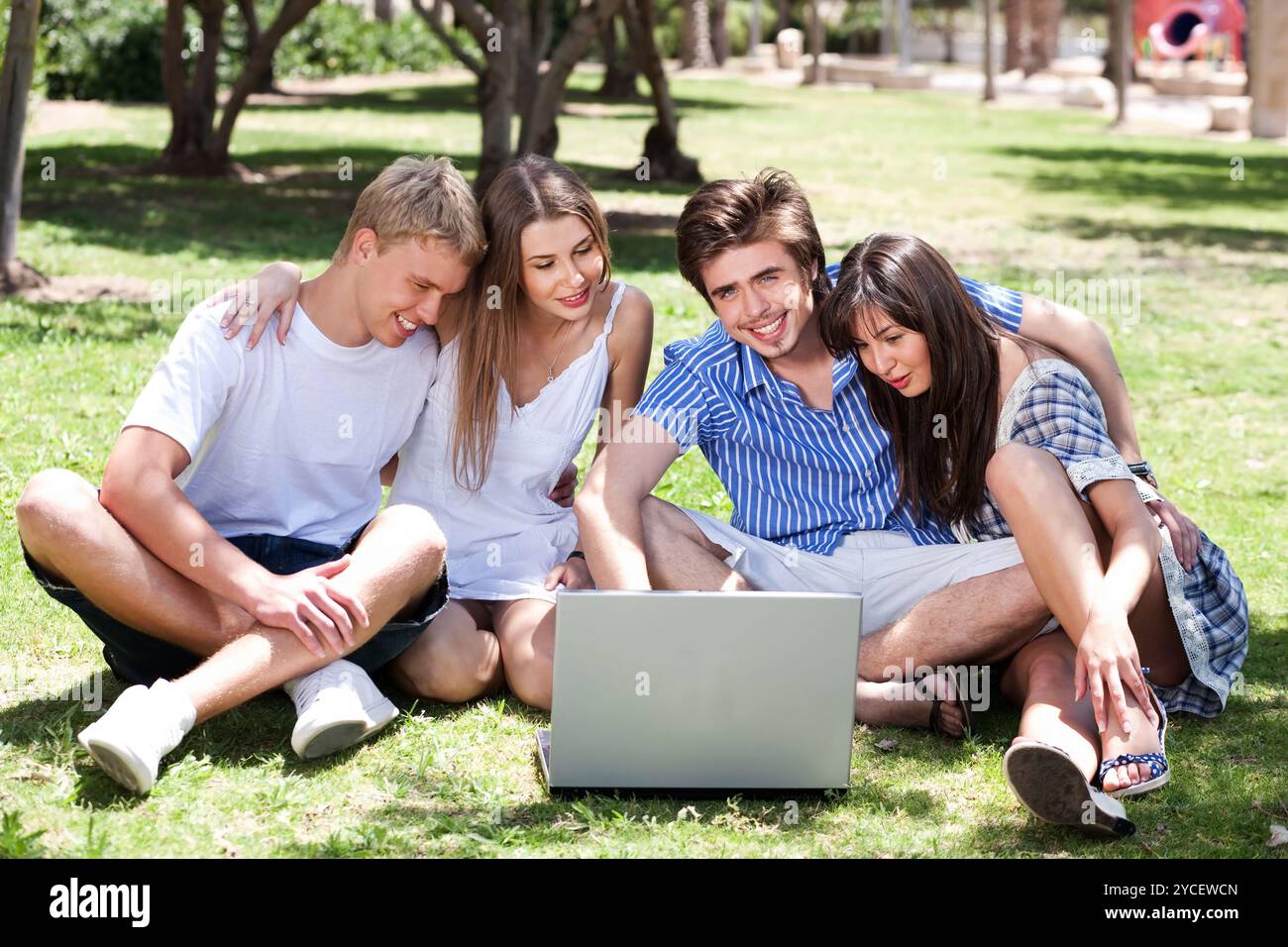 Friends film dans parc sur ordinateur portable et avoir beaucoup de temps aux beaux jours Banque D'Images