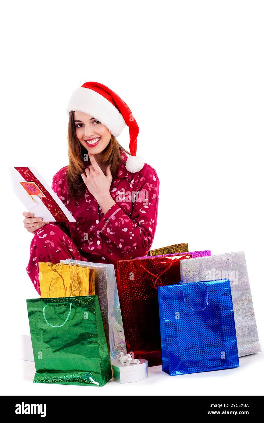 Jeune femme lisant la carte de noël entourée de sacs cadeaux Banque D'Images