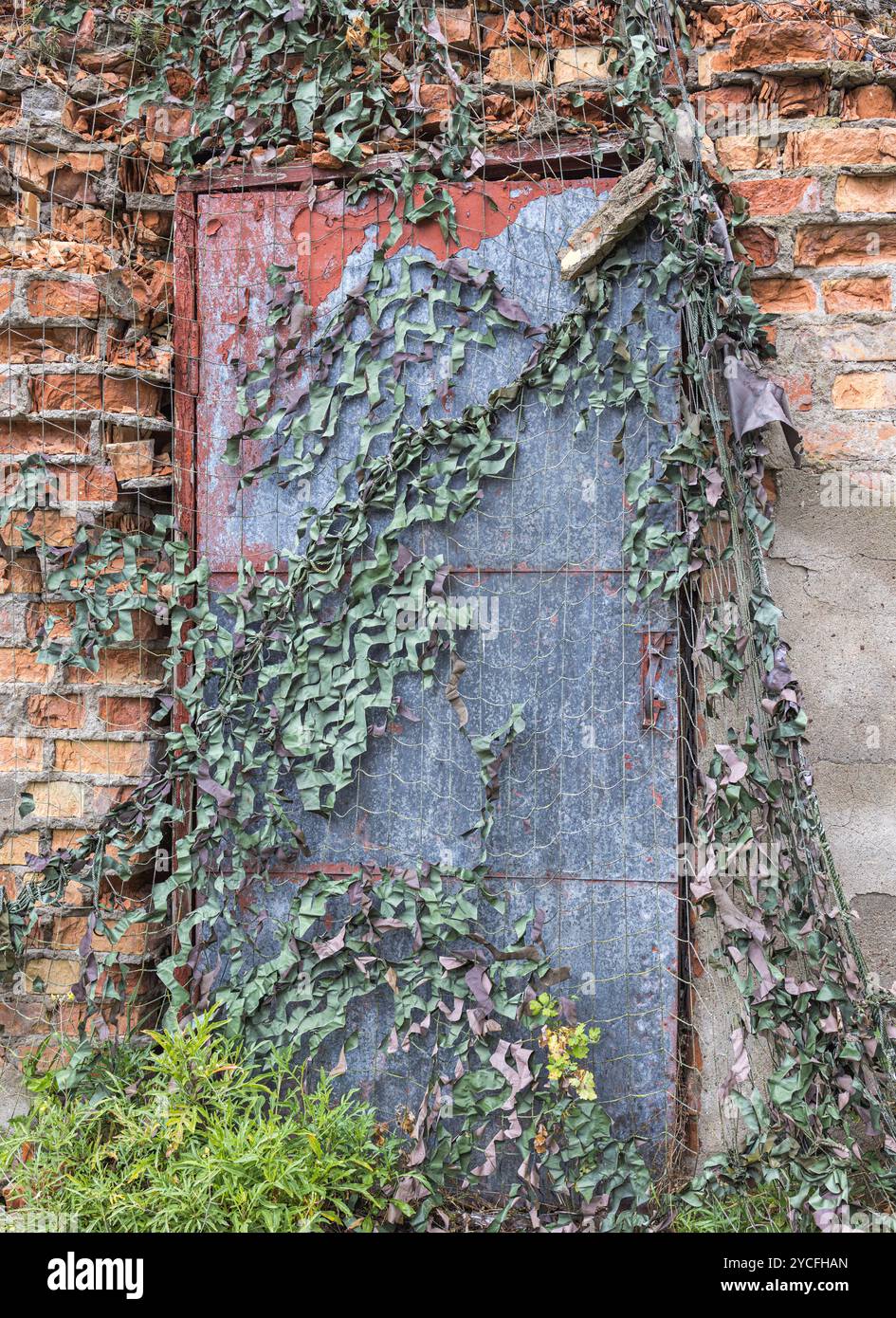 Bâtiment abandonné, porte avec filet de camouflage Banque D'Images