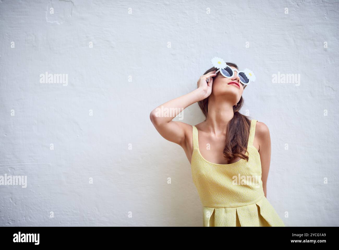Mur, femme et Marguerite dans des lunettes de soleil pour la mode, style tendance et sourire avec la pose pour la fierté. Personne féminine, confiance et fleurs avec accessoire pour Banque D'Images