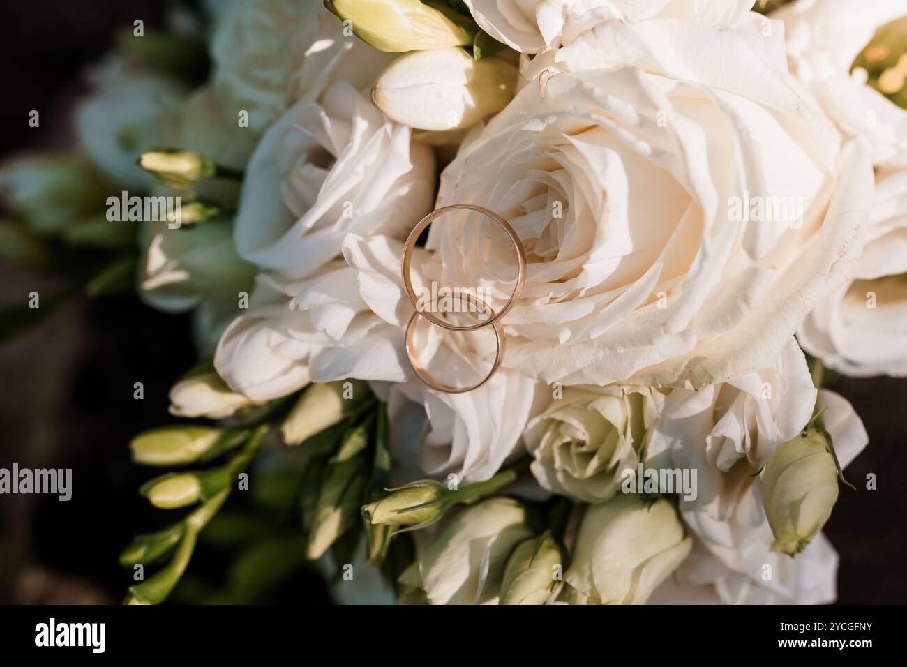 Élégant bouquet de mariage avec anneaux d'or entrelacés parmi les roses blanches. Banque D'Images