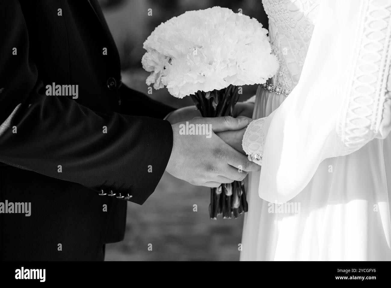 Moment intime d'une mariée et mariée tenant la main avec un bouquet de fleurs blanches. Banque D'Images