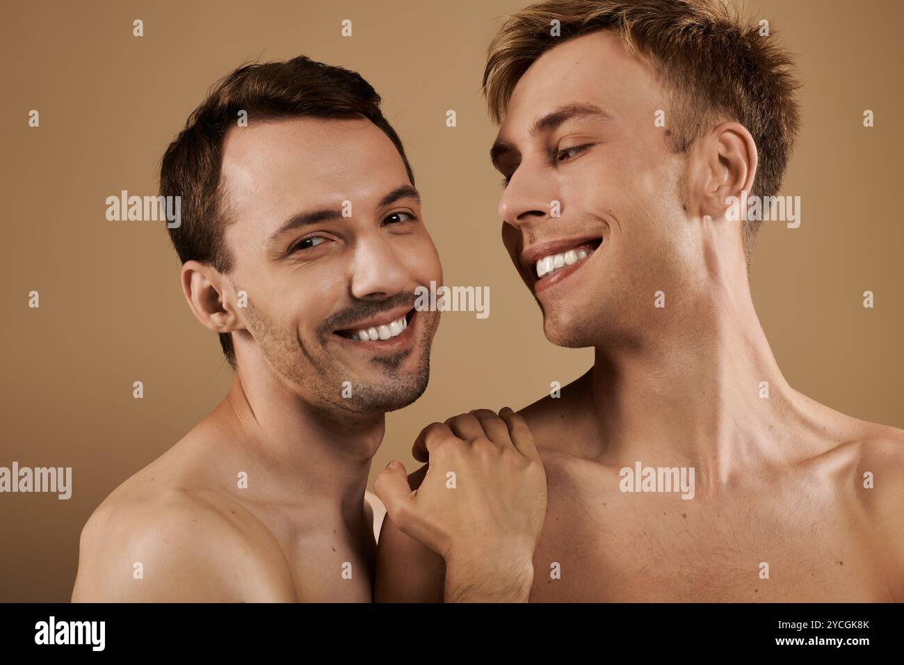 Deux jeunes hommes s’embrassent, rayonnant de bonheur et d’amour dans un cadre cosy et chaleureux. Banque D'Images