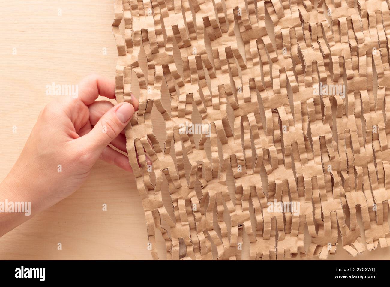 Papier nid d'abeille respectueux de l'environnement dans les mains, forme hexagonale, papier en carton recyclé brun élastique fort pour emballage protecteur, ami écologique Banque D'Images