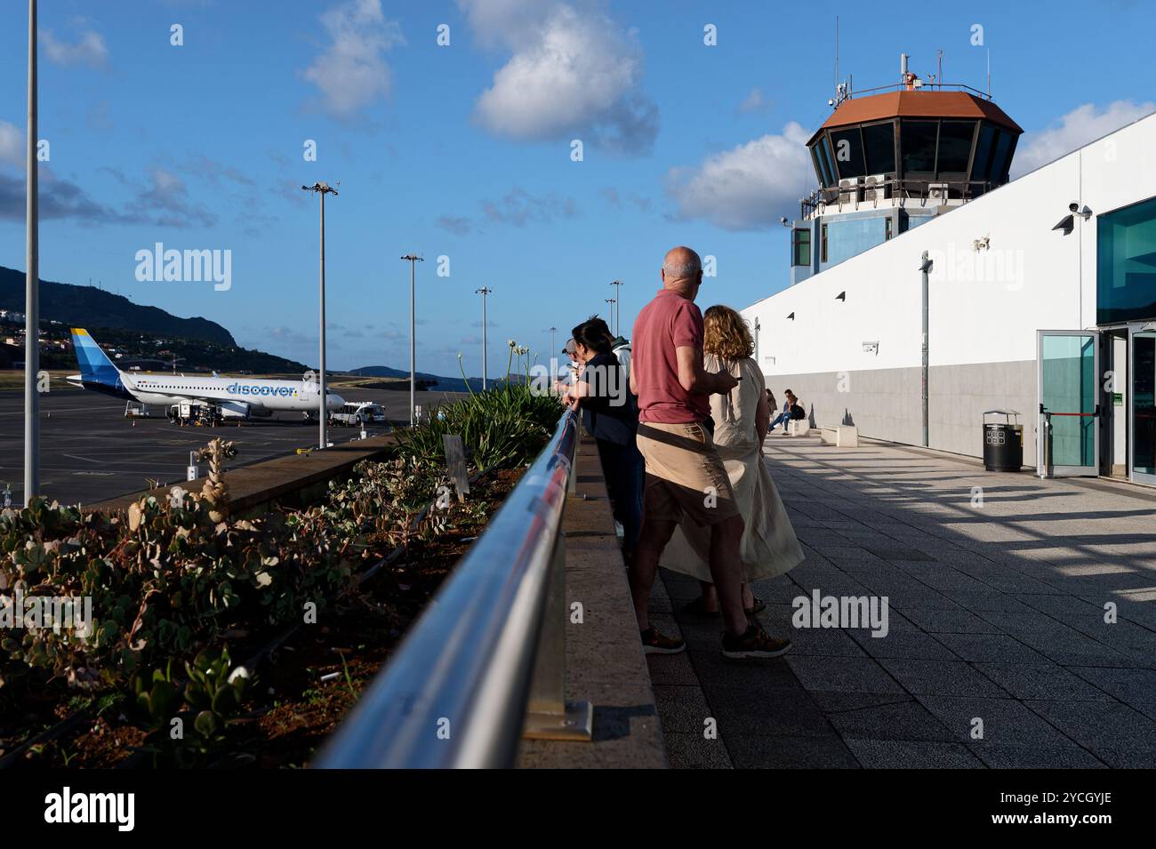 Les passagers profitent de la vue depuis le pont d'observation de l'aéroport de Funchal, tandis que les avions se préparent à partir sous le soleil chaud de l'après-midi Banque D'Images Les passagers profitent de la vue depuis le pont d'observation de l'aéroport de Funchal, tandis que les avions se préparent à partir sous le soleil chaud de l'après-midi Banque D'Images
