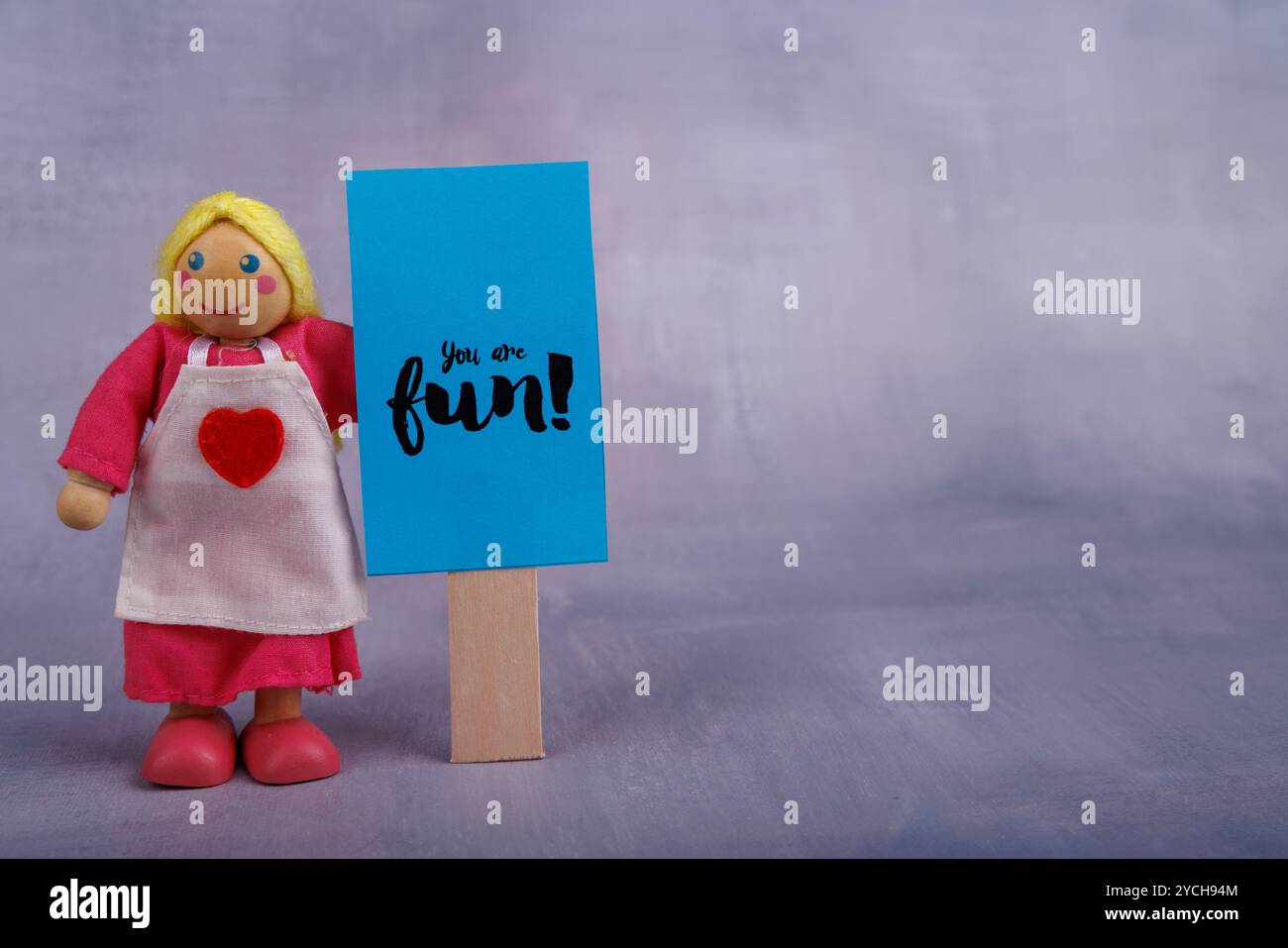 Une poupée en bois est vue tenant un panneau bleu avec un message de motivation. La photo transmet énergie positive, optimisme et simplicité Banque D'Images