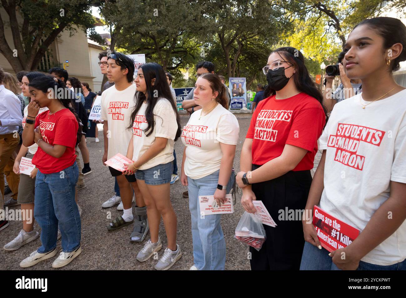 Austin Texas USA, 22 octobre 2024 : des étudiants de l'Université du Texas portant des chemises « Students Demand action » écoutent le défenseur du contrôle des armes à feu David Hogg (non montré) lors d'un événement de sortie du vote sur le campus. Hogg, 24 ans, fondateur de March for Our Lives, était un étudiant de 17 ans à l’école secondaire Marjory Stoneman Douglas à Parkland, en Floride, lorsqu’un homme armé a tué 17 de ses camarades de classe en 2018. ©Bob Daemmrich Banque D'Images