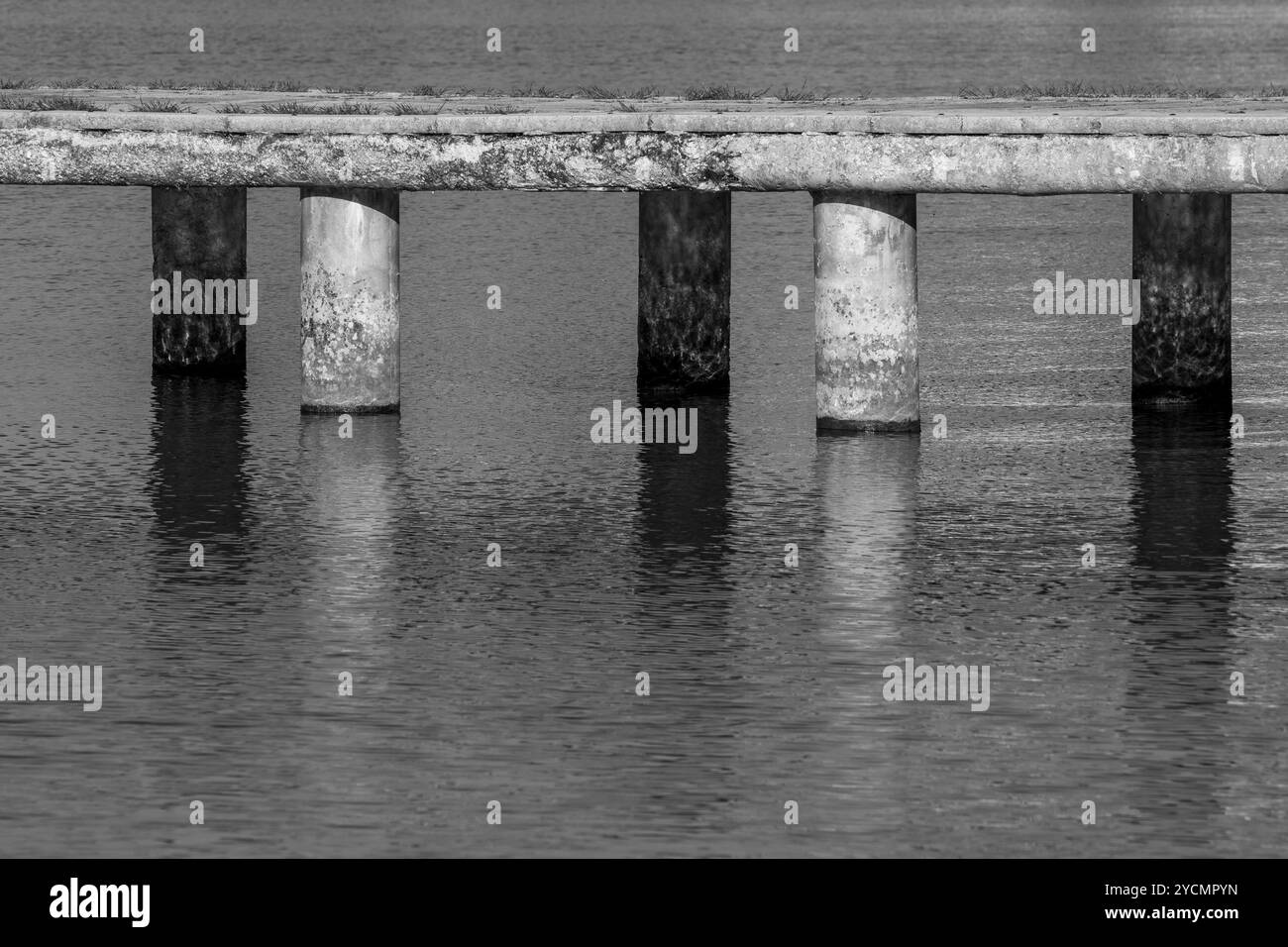 Réflexions en équilibre : piliers en béton de la jetée du lac Ohrid dans lumière et ombre Banque D'Images