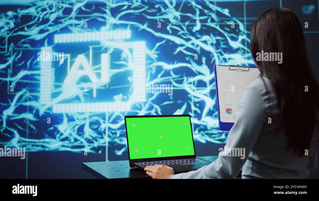 Employé de démarrage regardant les graphiques, en utilisant un logiciel d'IA sur ordinateur portable à écran vert pour prendre des décisions basées sur les données. Femme indienne développant des solutions innovantes d'intelligence artificielle pour l'entreprise, caméra B. Banque D'Images
