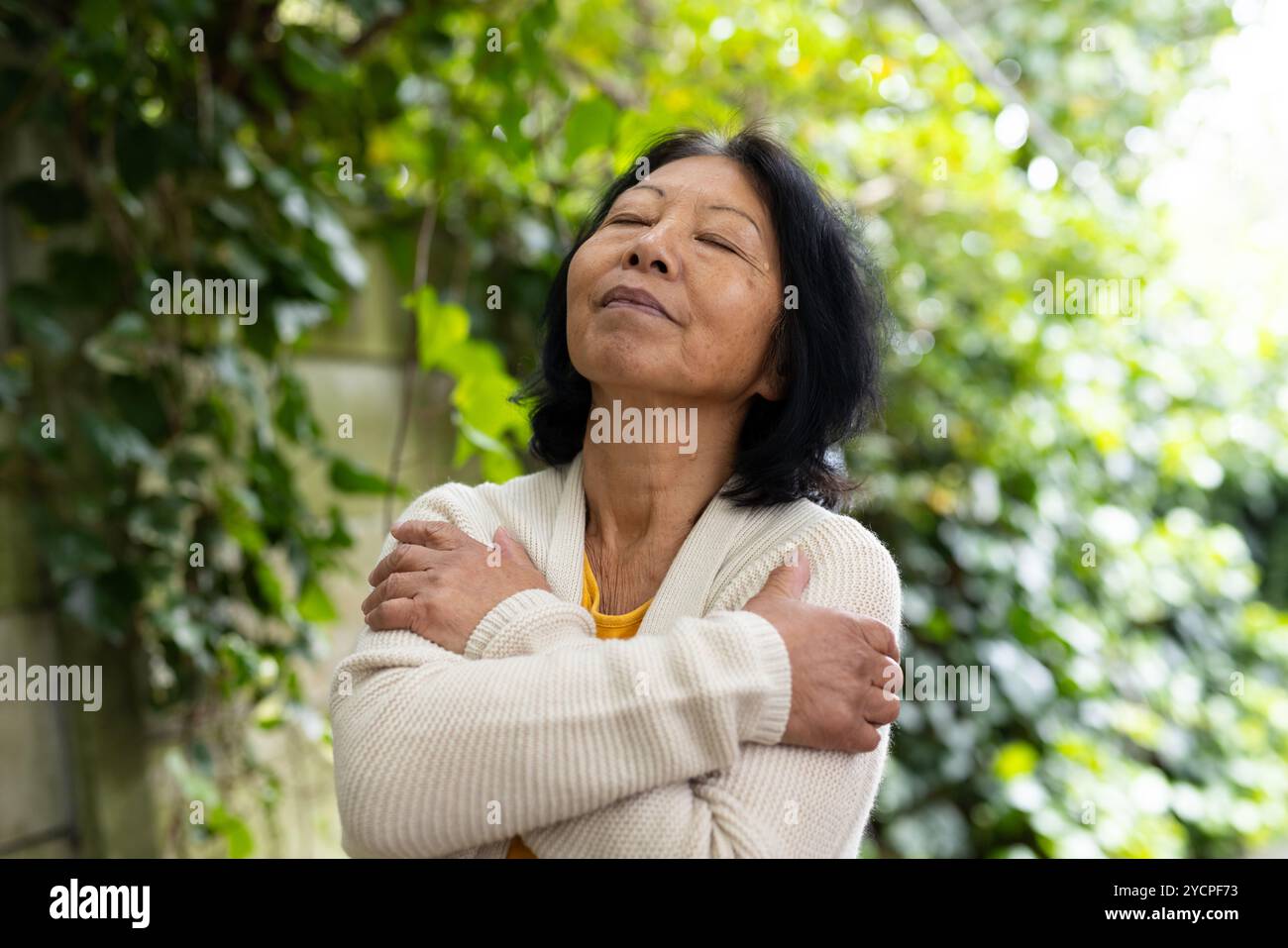 femme senior asiatique s'embrassant à l'extérieur, profitant de la solitude paisible dans la nature Banque D'Images