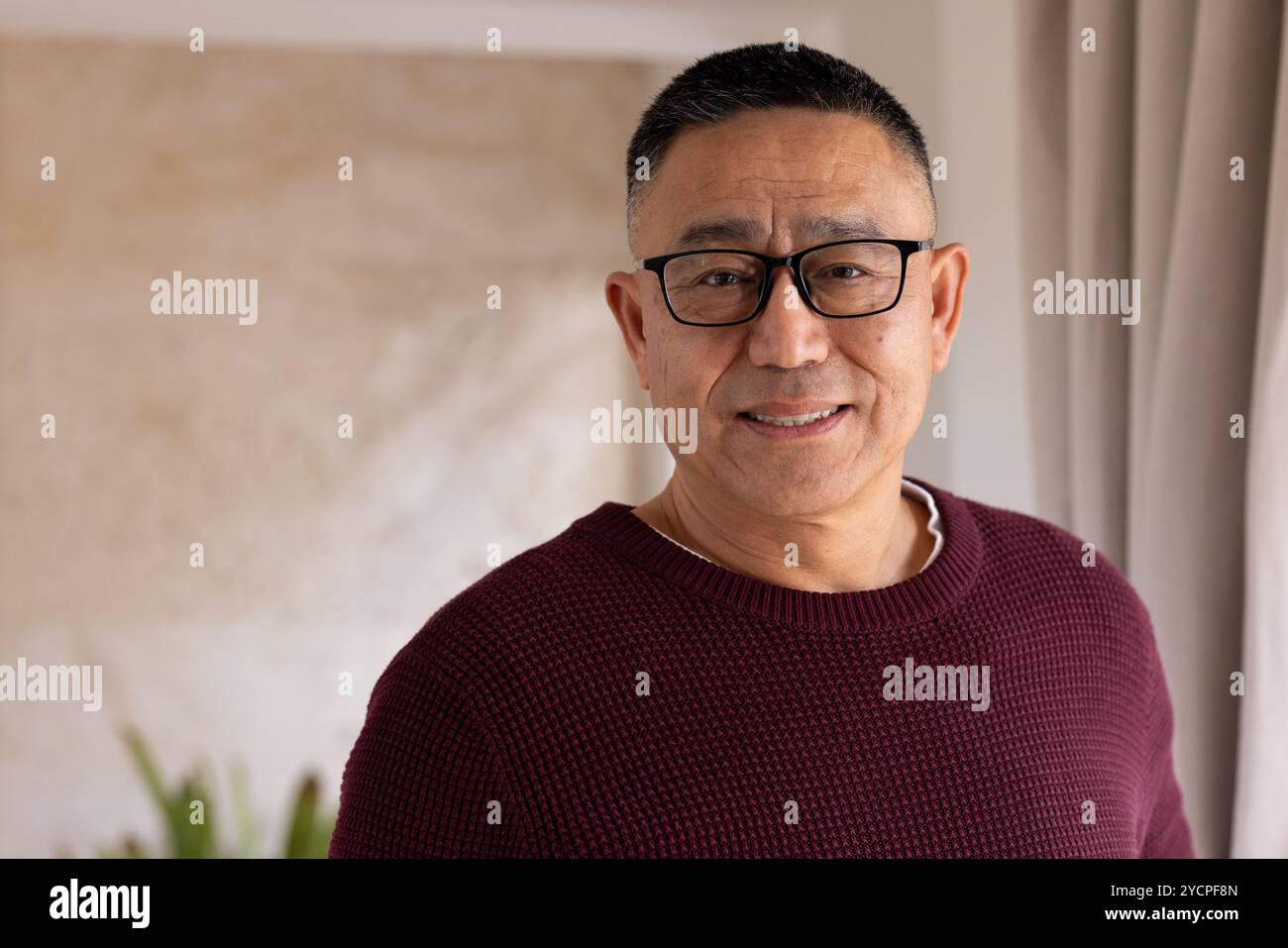 Homme senior asiatique souriant portant des lunettes et un pull debout à la maison pendant Noël, copiez l'espace Banque D'Images