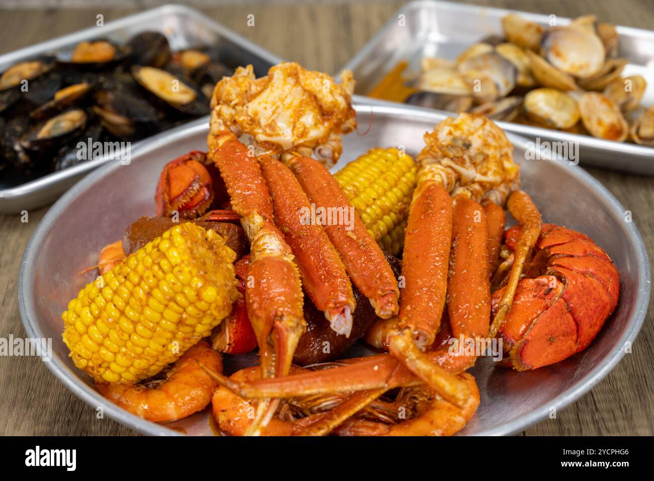 Dégustez des fruits de mer cajun avec choix de crustacés pour le souper avec des pattes de crabe des neiges, du homard, du maïs et des crevettes à l'avant. Banque D'Images