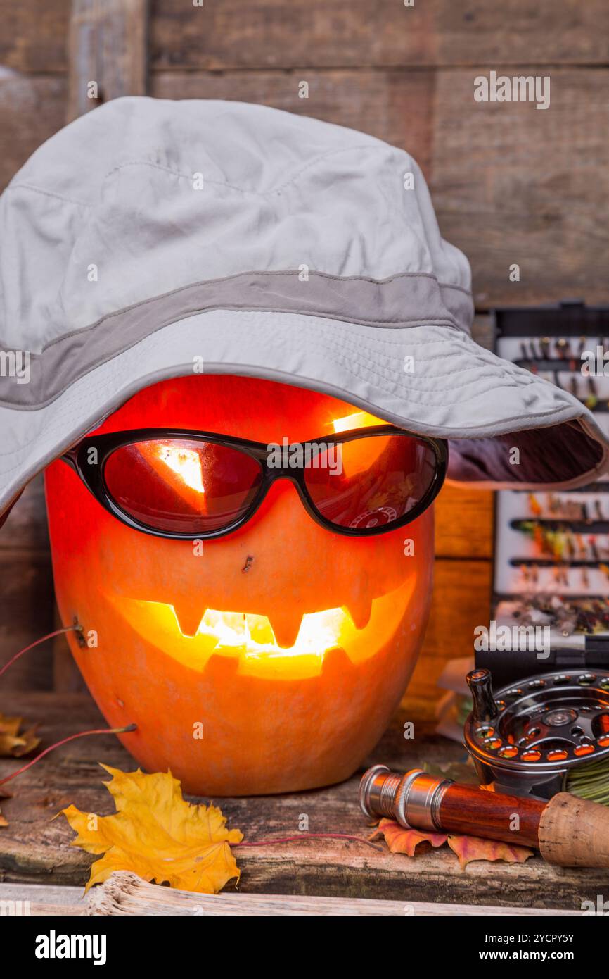 Citrouille d'Halloween dans un chapeau avec des tacles de pêche à la mouche Banque D'Images Citrouille d'Halloween dans un chapeau avec des tacles de pêche à la mouche Banque D'Images