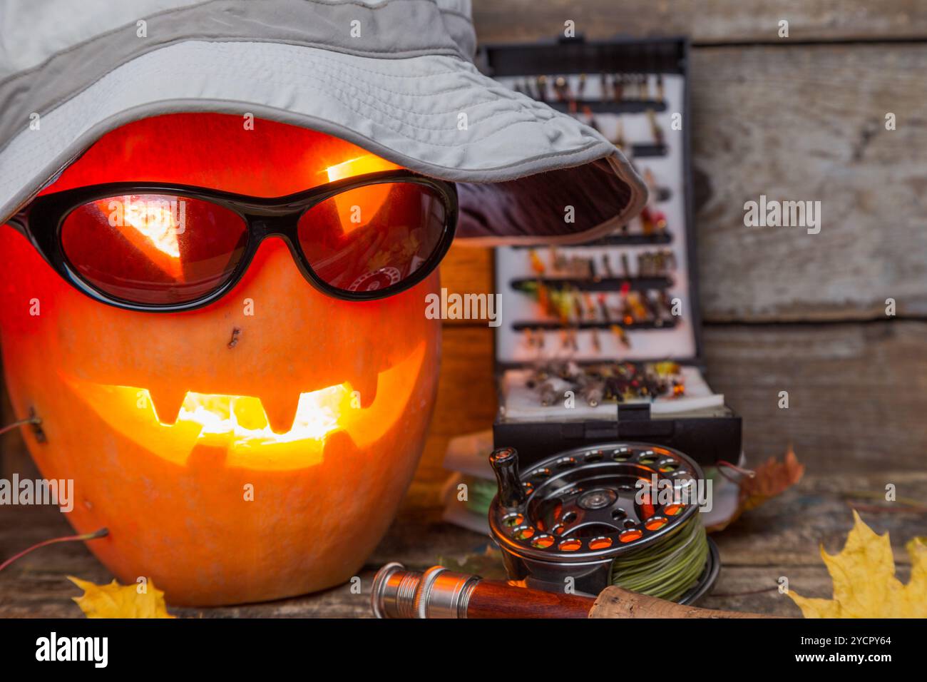 Citrouille d'Halloween dans un chapeau avec des tacles de pêche à la mouche Banque D'Images Citrouille d'Halloween dans un chapeau avec des tacles de pêche à la mouche Banque D'Images