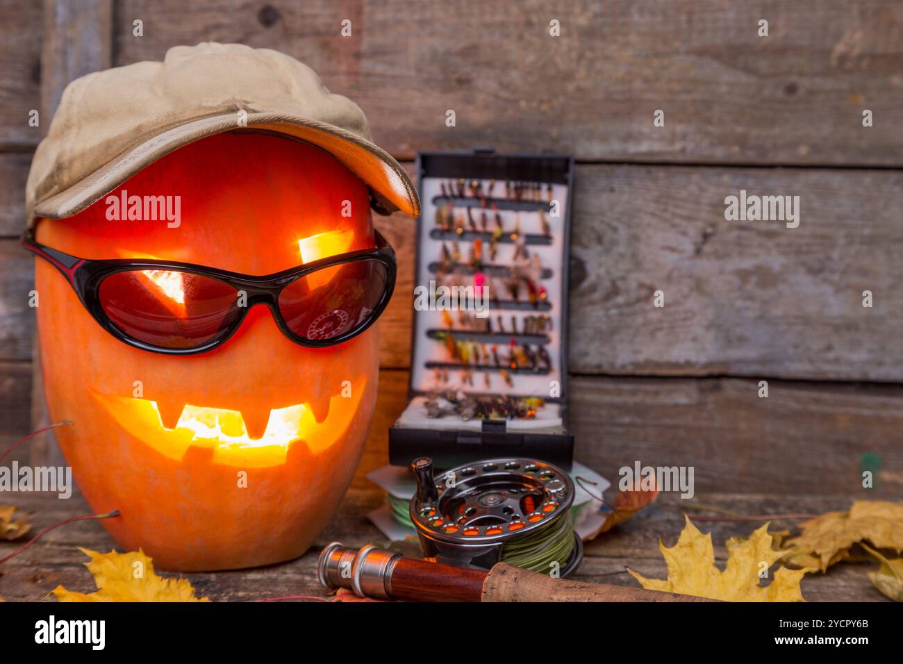 Citrouille d'Halloween dans un chapeau avec des tacles de pêche à la mouche Banque D'Images Citrouille d'Halloween dans un chapeau avec des tacles de pêche à la mouche Banque D'Images