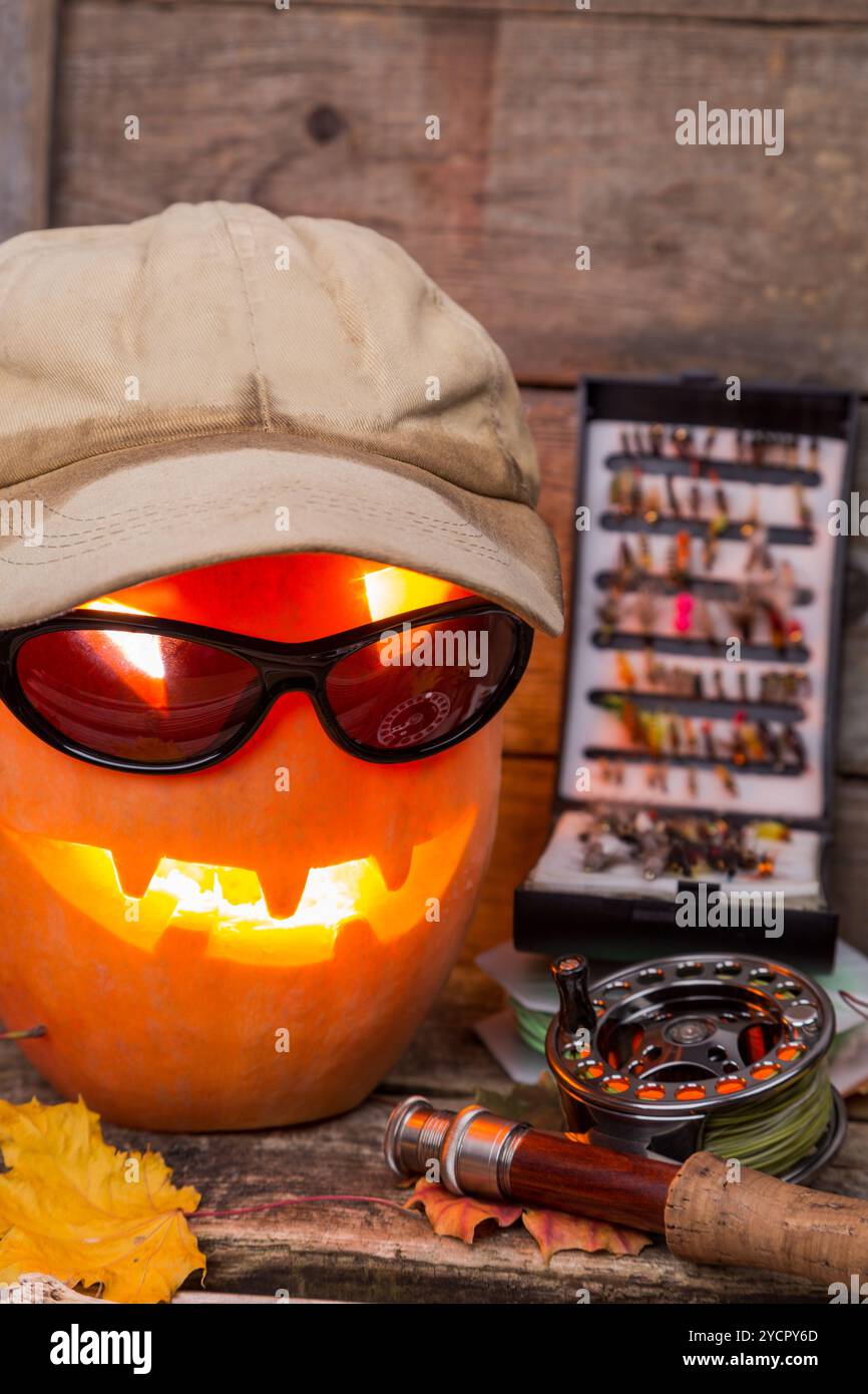 Citrouille d'Halloween dans un chapeau avec des tacles de pêche à la mouche Banque D'Images Citrouille d'Halloween dans un chapeau avec des tacles de pêche à la mouche Banque D'Images
