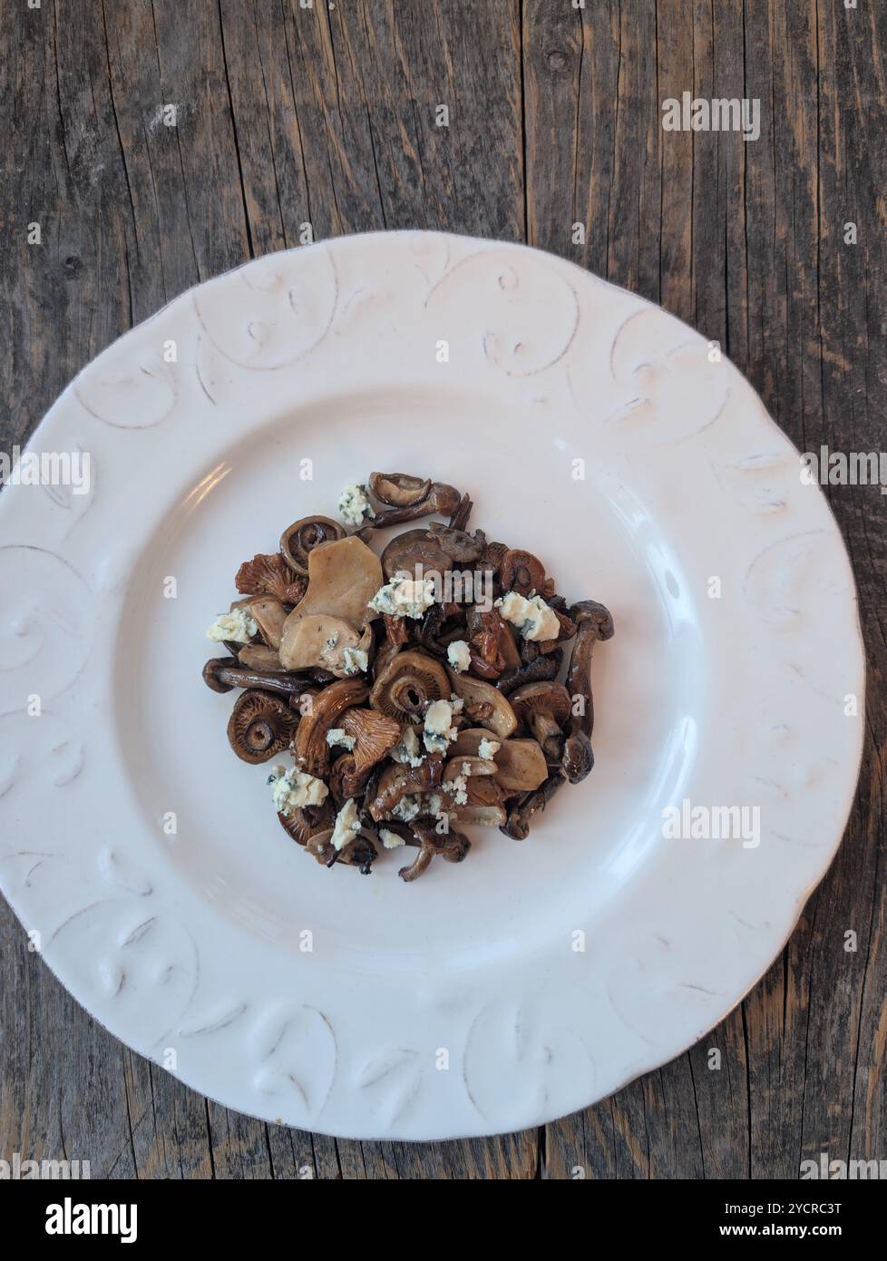 Une salade de champignons avec du fromage bleu sur une assiette blanche Banque D'Images