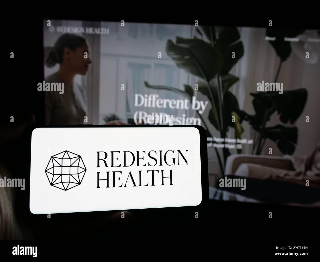 Personne tenant un smartphone avec le logo de la société de soins de santé américaine Redesign Health Inc sur l'écran devant le site Web. Concentrez-vous sur l'affichage du téléphone. Banque D'Images