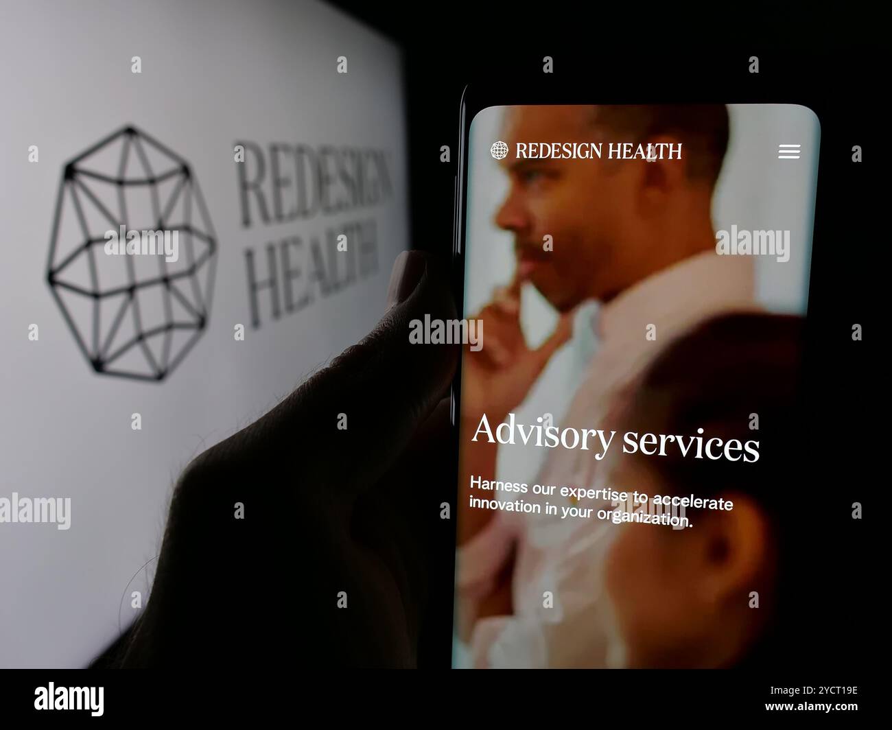 Personne tenant le téléphone portable avec le site Web de la société de soins de santé américaine Redesign Health Inc sur l'écran avec le logo. Concentrez-vous sur le centre de l'écran du téléphone. Banque D'Images