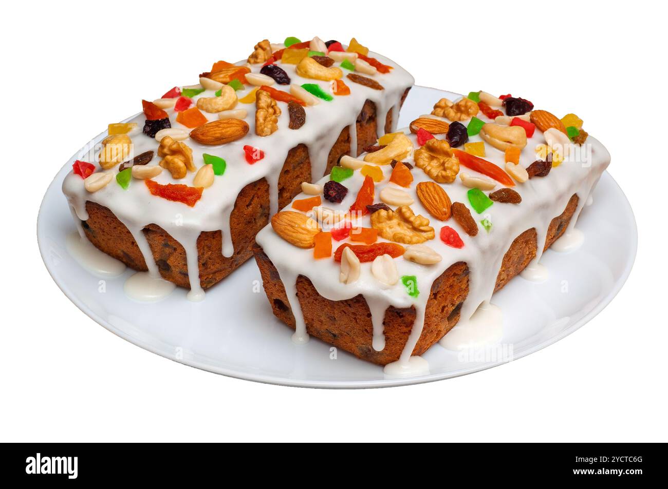 Gâteaux aux fruits de Noël avec glaçage blanc, garnis de fruits secs et de noix sur une assiette blanche. Banque D'Images