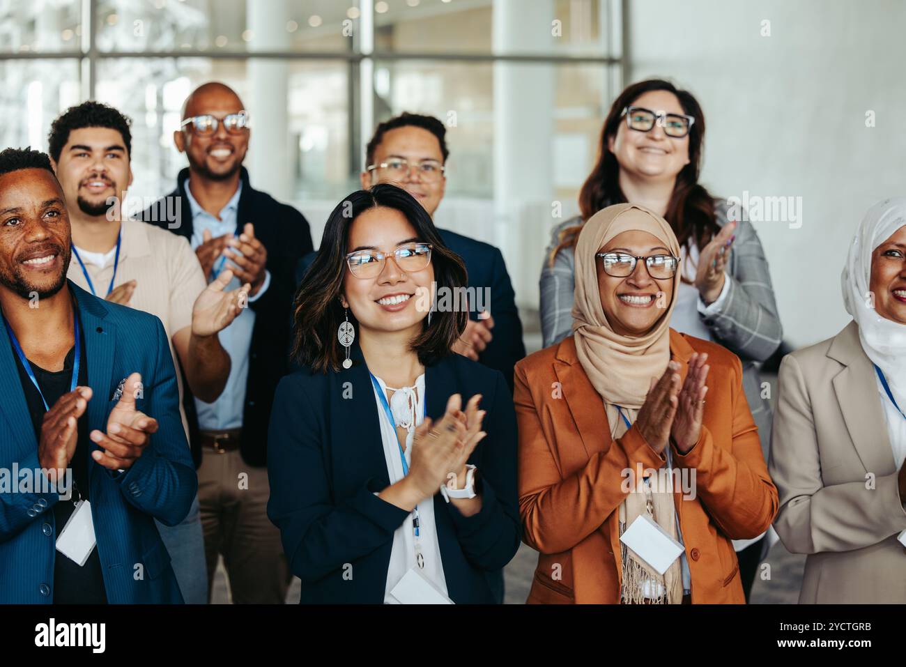 Un groupe diversifié de professionnels affichant du bonheur tout en applaudissant lors d'un séminaire. Ils reflètent l'engagement et l'énergie positive dans une entreprise en Banque D'Images