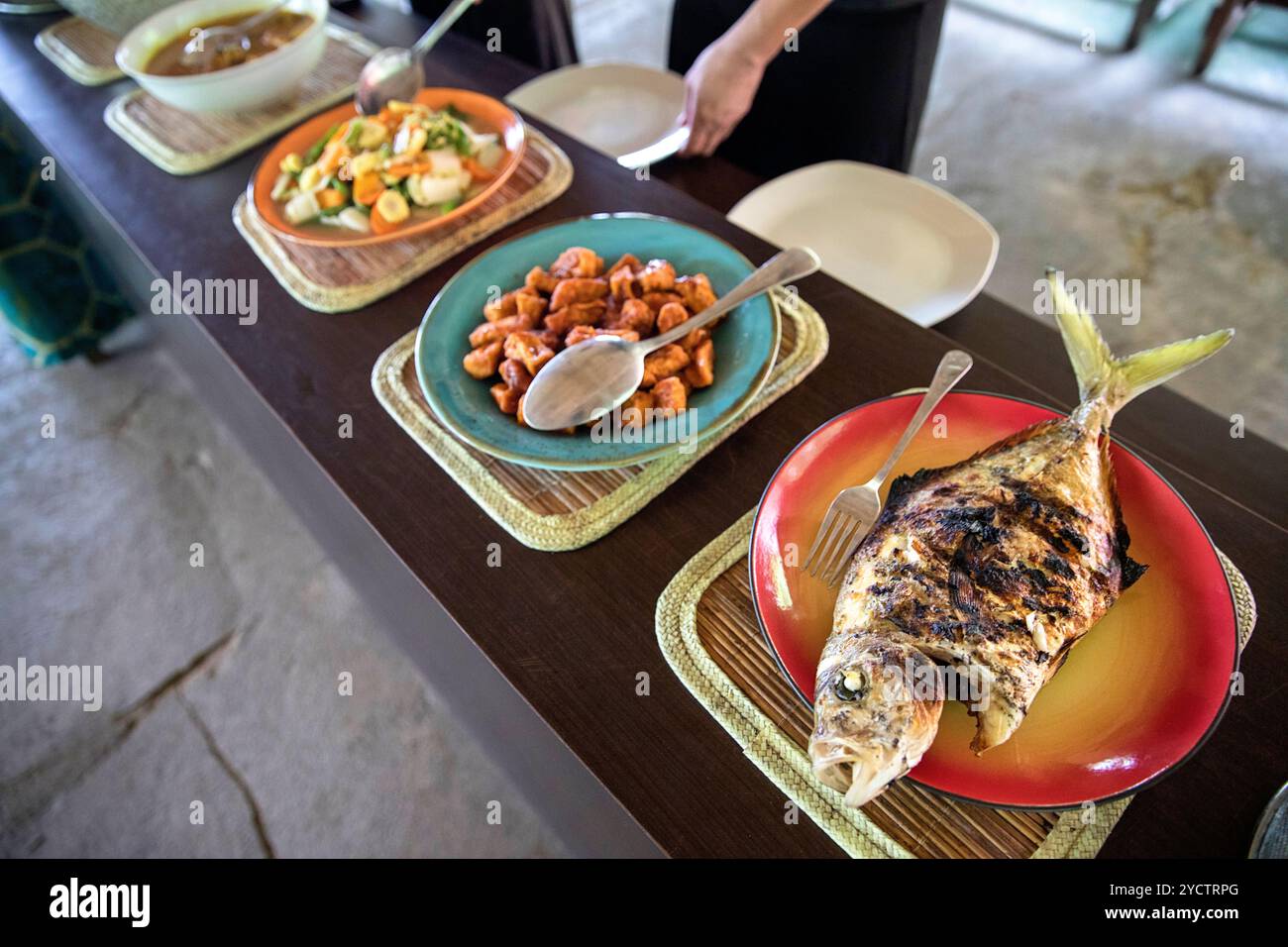 Une délicieuse assiette de poisson grillé traditionnel indonésien servi avec des accompagnements locaux et du sambal, mettant en valeur la cuisine authentique de Sulawesi. Banque D'Images