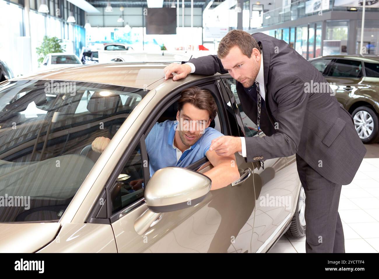 Conseils dans la concession automobile - vendeur et jeune homme vendant une nouvelle voiture Banque D'Images