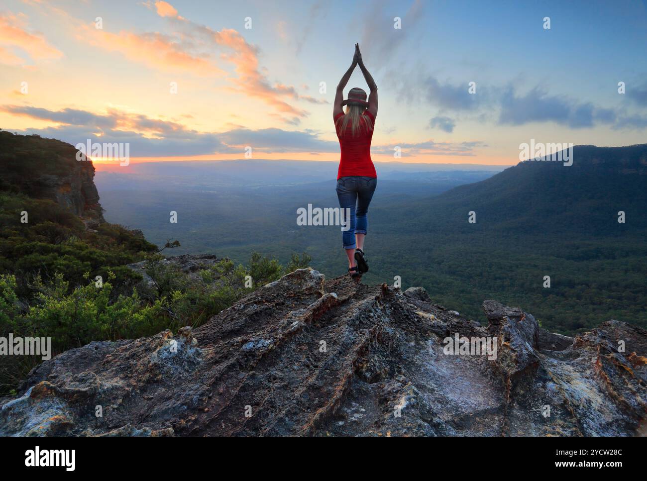 Bras tendus, tendez la main vers le ciel. Tenez-vous debout sur les orteils piqués, oh, oh, si haut. Femme sur le bord d'une falaise de montagne avec vue sur la vallée étire ses bras Banque D'Images