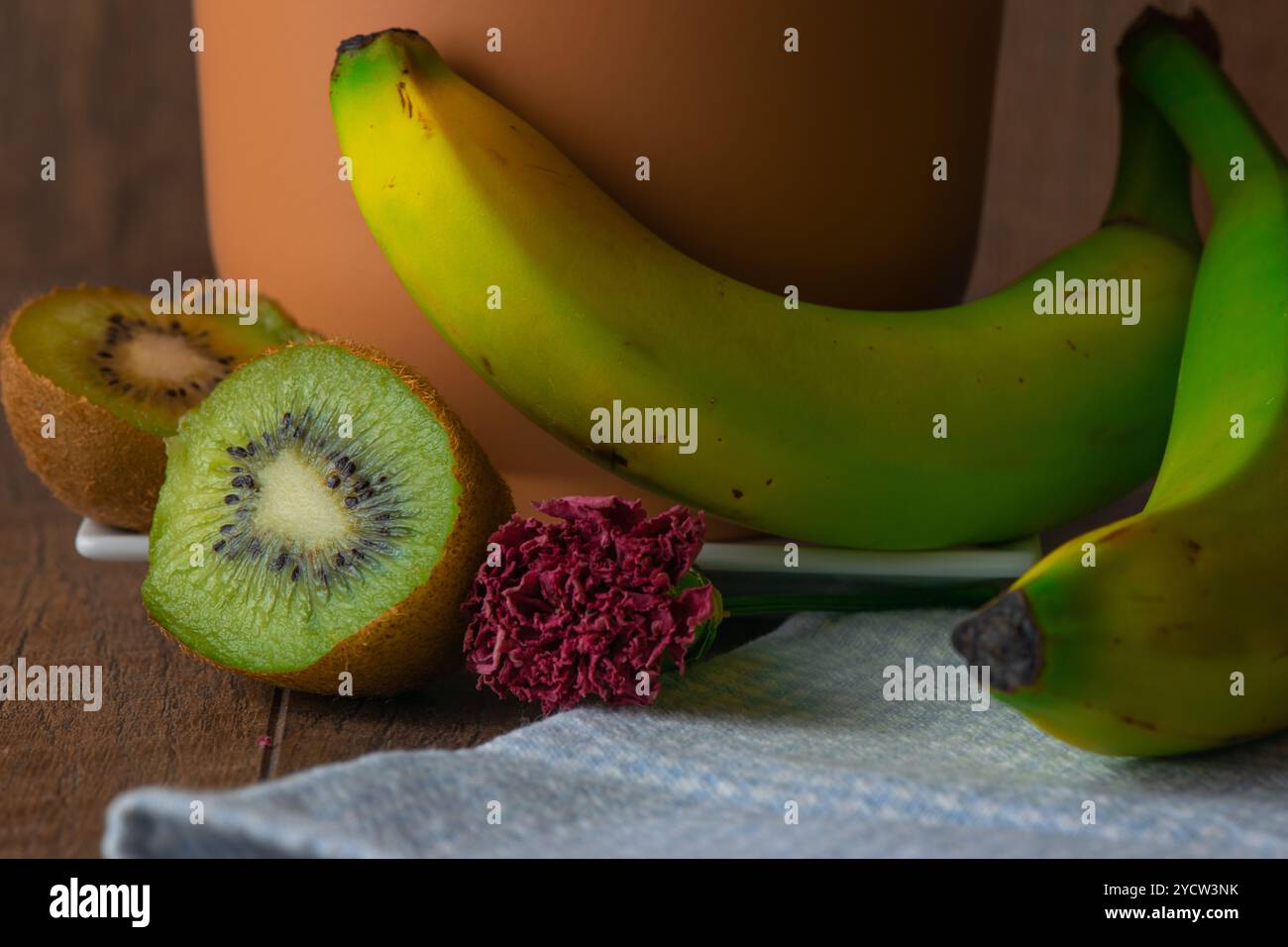 Nature morte avec kiwi, fleur rouge foncé et banane près d'un vase Banque D'Images