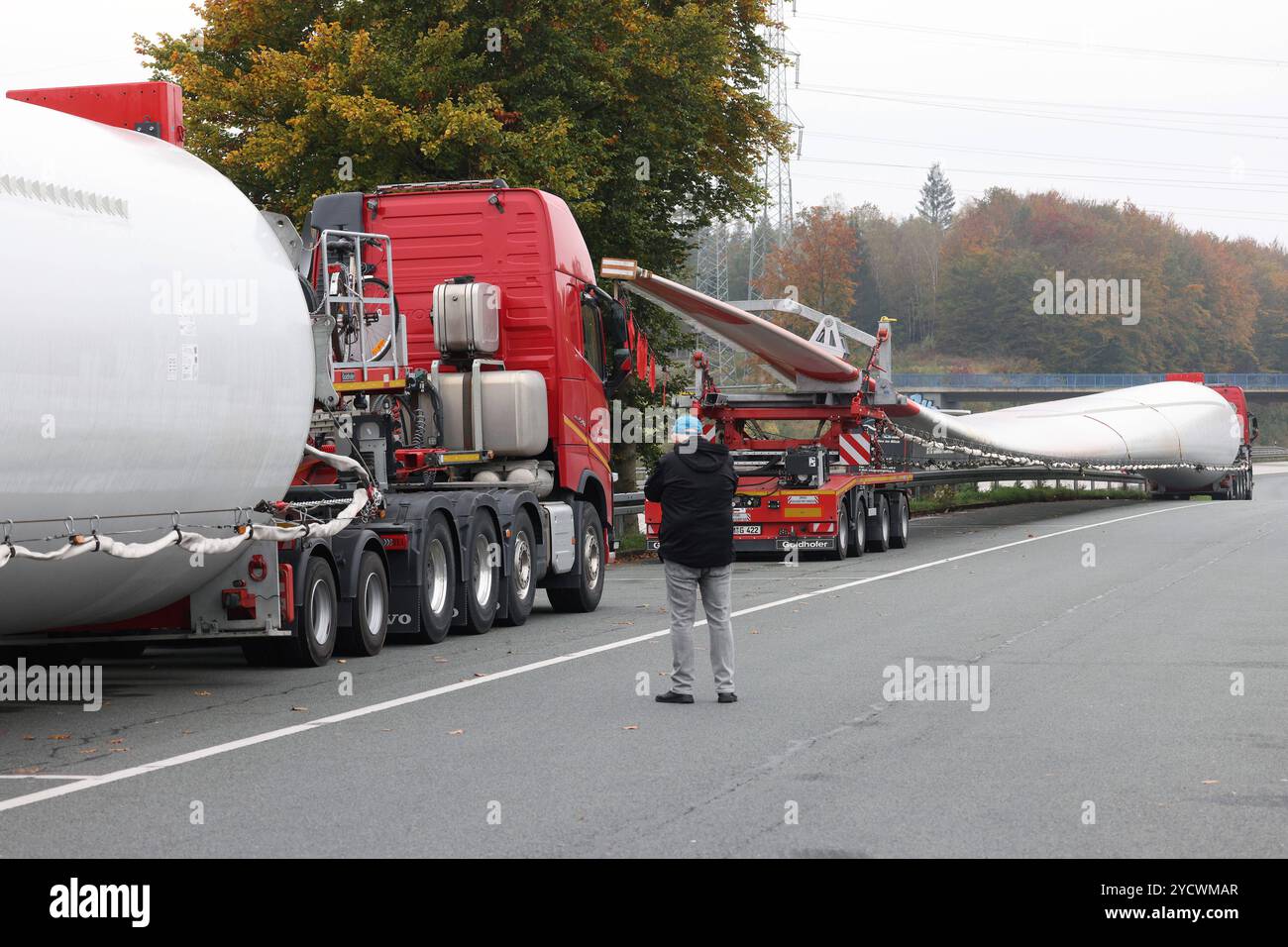 Schwertransporter mit Rotorblaettern Rotorblättern fuer für ein Windrad stehen auf dem Parkplatz der Raststaette Raststätte Siegerland Ost an der Autobahn A45. IM Vordergrund Steht ein Mann. Schwertransport im Siegerland AM 24.10.2024 à Freudenberg/Deutschland. *** Transporteur lourd avec pales de rotor pales de rotor pour un stand d'éolienne dans le parking de l'arrêt de repos Raststaette Siegerland Ost sur l'autoroute A45 au premier plan est un transport lourd MAN à Siegerland le 24 10 2024 à Freudenberg Allemagne Banque D'Images