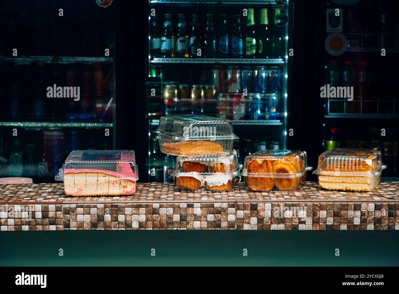 Une gamme de produits de boulangerie emballés exposés sur un comptoir carrelé à l'intérieur d'un magasin à El Salvador, en Amérique centrale, avec un réfrigérateur rempli de bever Banque D'Images