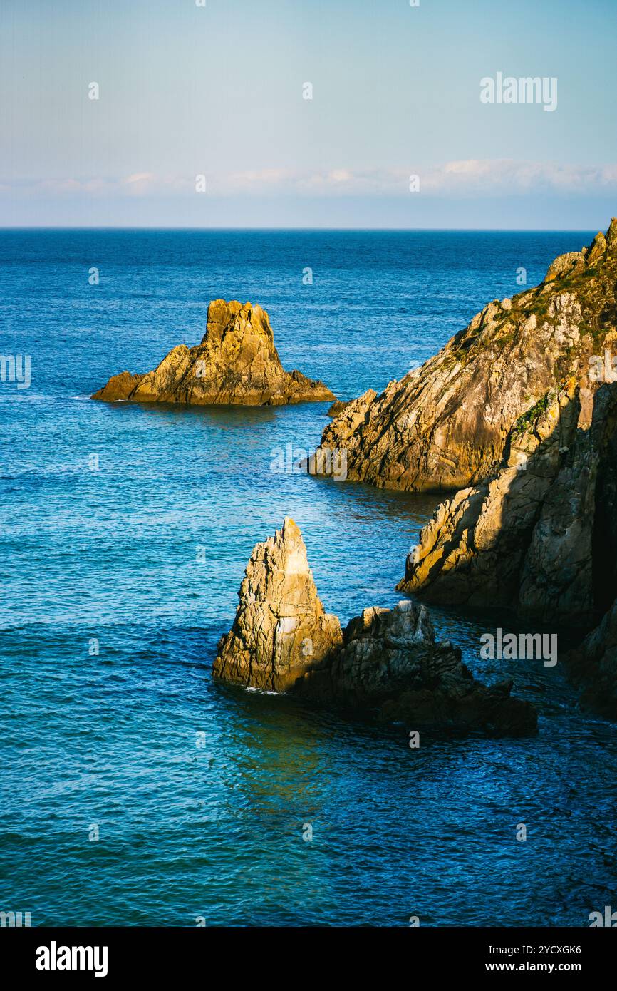 Superbe image aérienne de falaises escarpées et d'affleurements rocheux le long de la côte galicienne, baignée de soleil avec l'océan bleu clair qui jaillit doucement Banque D'Images