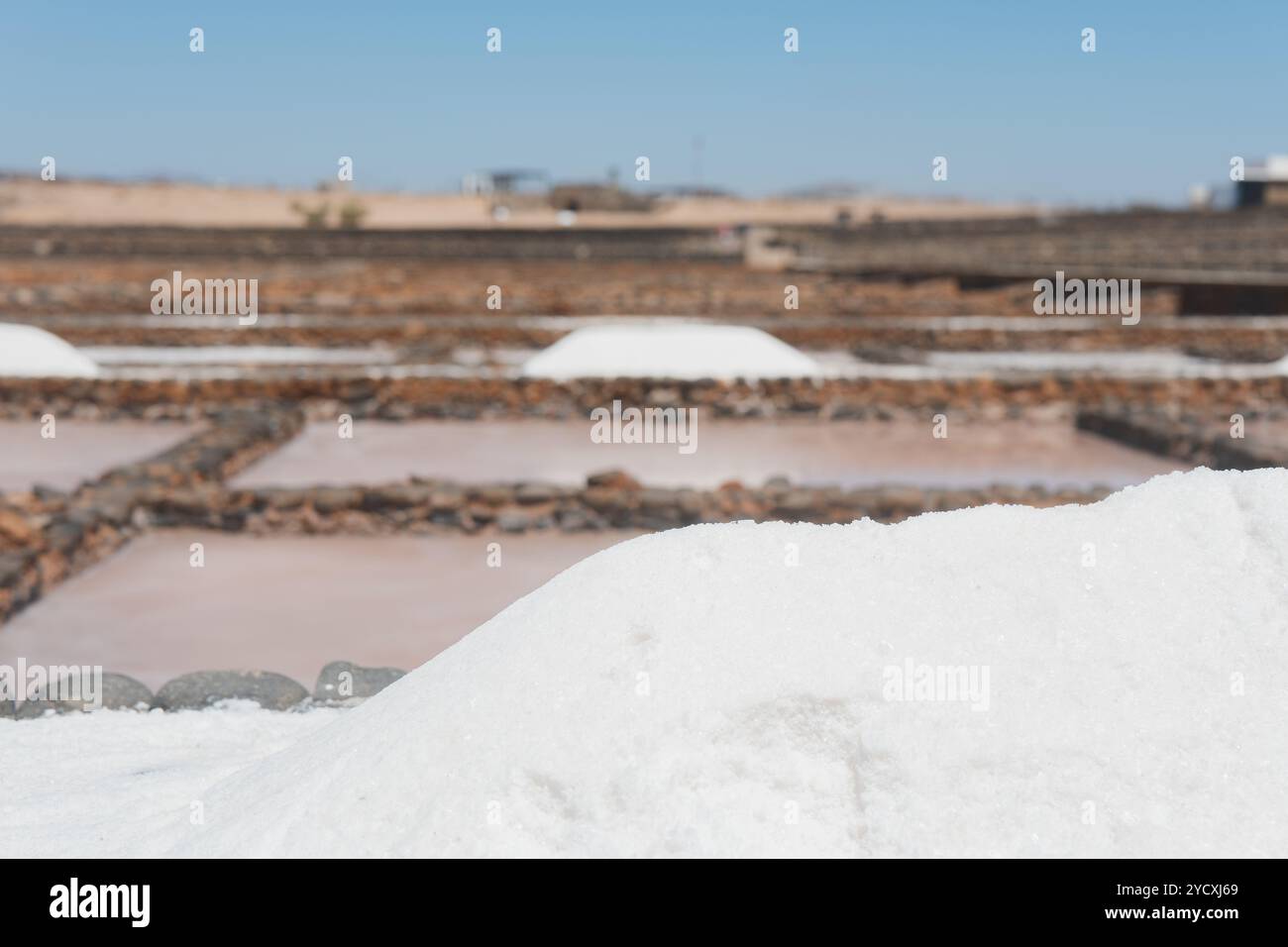 Vue panoramique des monticules de sel et des piscines d'évaporation pour la production de sel sous un ciel bleu clair, représentant la méthode traditionnelle d'extraction du sel Banque D'Images