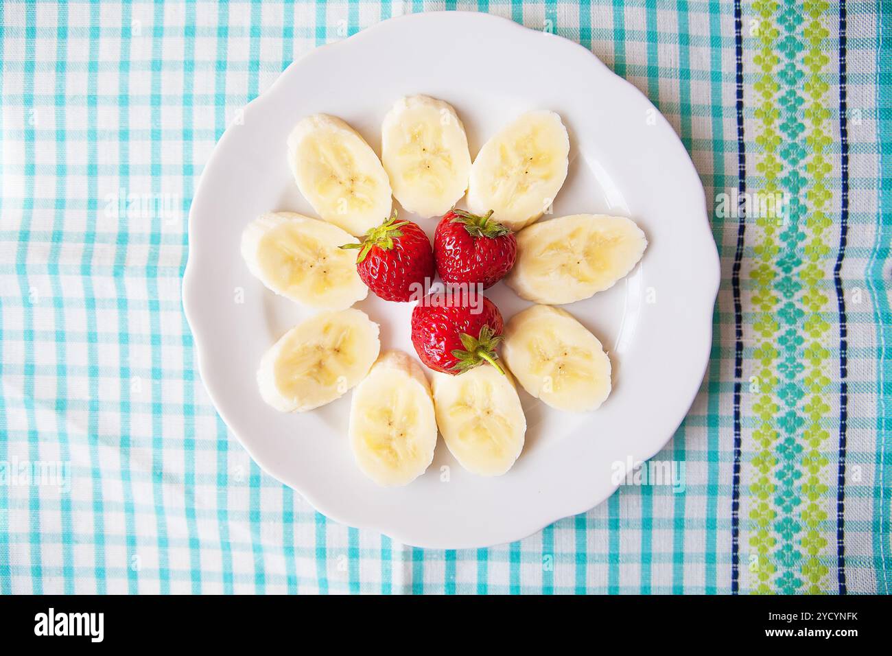 Banane et fraises sur une assiette blanche et une serviette colorée Banque D'Images