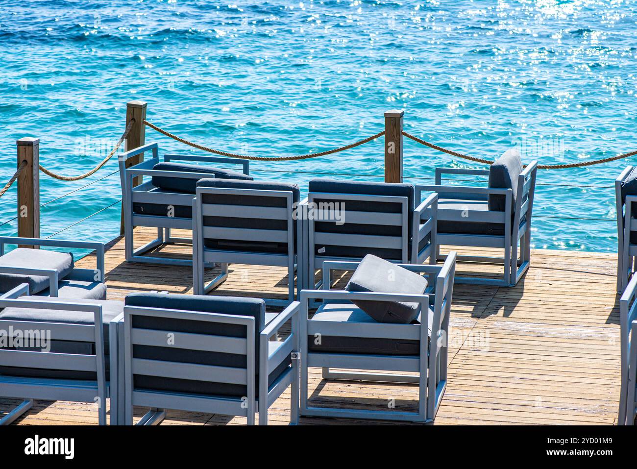 Sièges confortables et canapés disposés en bord de mer sous un ciel ensoleillé, offrant l'endroit idéal pour se détendre et profiter d'une vue imprenable sur l'océan. Banque D'Images
