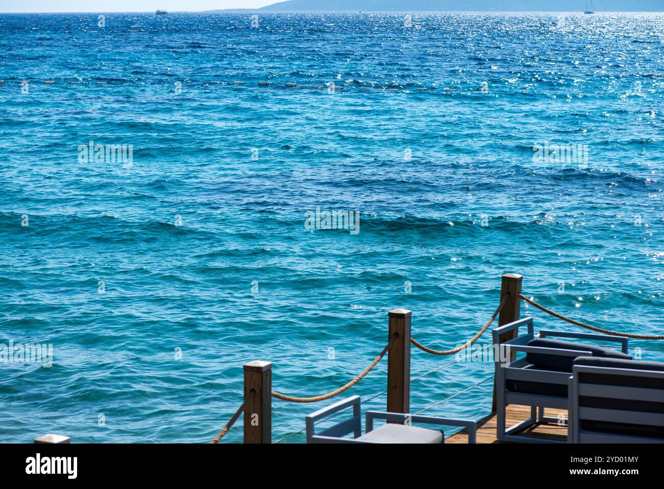 Sièges confortables et canapés disposés en bord de mer sous un ciel ensoleillé, offrant l'endroit idéal pour se détendre et profiter d'une vue imprenable sur l'océan. Banque D'Images