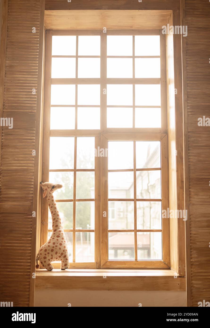 girafe jouet en peluche souple sur un rebord de fenêtre en bois. journées ensoleillées. chambre d'enfants. Banque D'Images