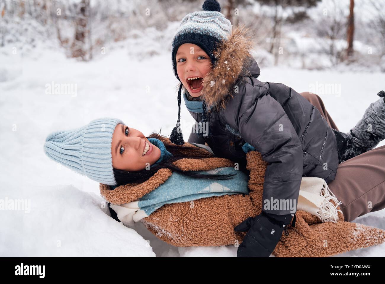 Une mère et son enfant jouent joyeusement dans un magnifique paysage enneigé, embrassant la joie de l'hiver ensemble Banque D'Images