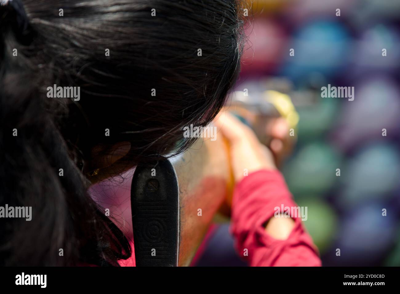 Une jeune femme se concentre sur sa cible, le fond coloré disparaît. Banque D'Images