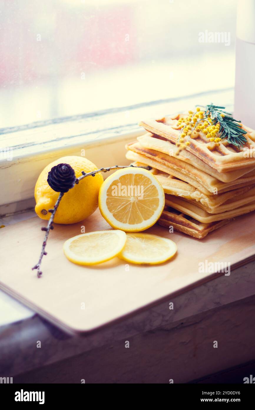 Gaufrettes viennoises empilées et tranchées de citron. Citron tranché sur une planche de bois. Les fruits sont hachés. Citron aigre. Banque D'Images