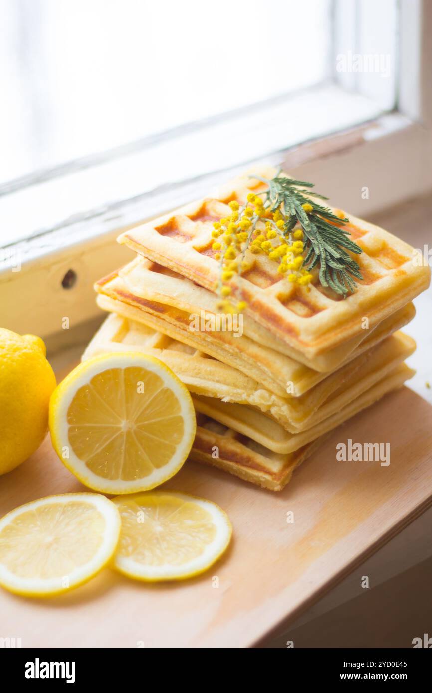 Gaufrettes viennoises empilées et tranchées de citron. Citron tranché sur une planche de bois. Les fruits sont hachés. Citron aigre. Banque D'Images