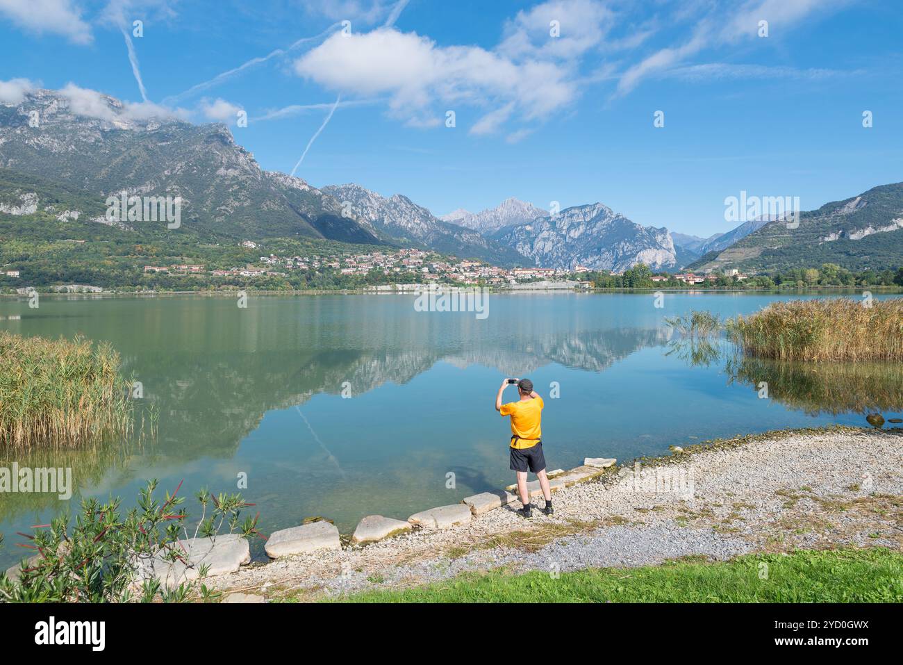 L'homme photographie un lac par une splendide journée ensoleillée. Lac Annone ou lac Oggiono, Italie. Panorama depuis la piste cyclable piétonne, Annone di Brianza Banque D'Images