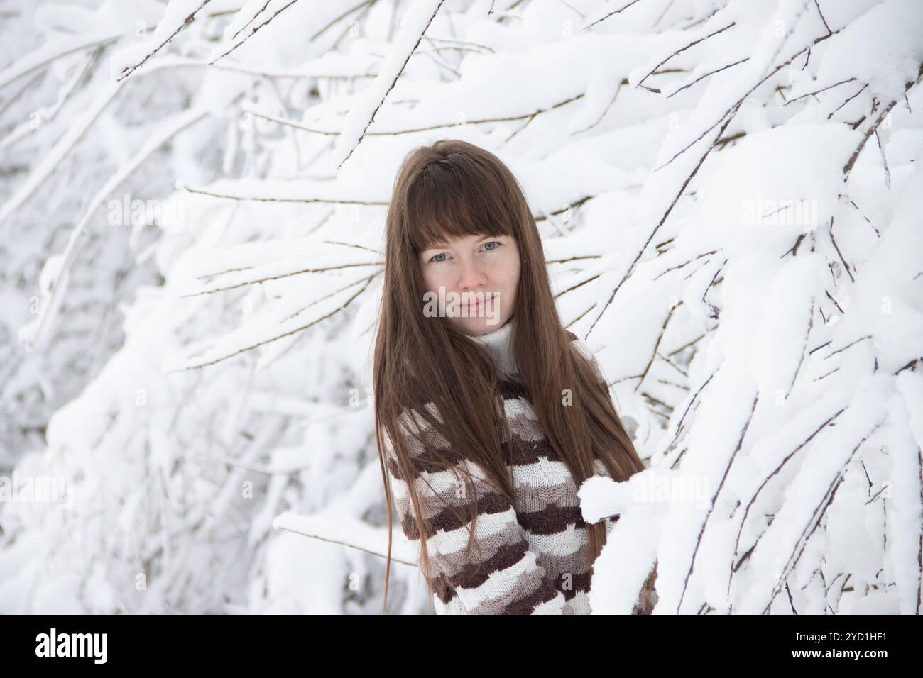 La fille en hiver en dehors de la ville. Fille sur un fond d'arbres enneigés dans un pull. Arbres enneigés. Banque D'Images