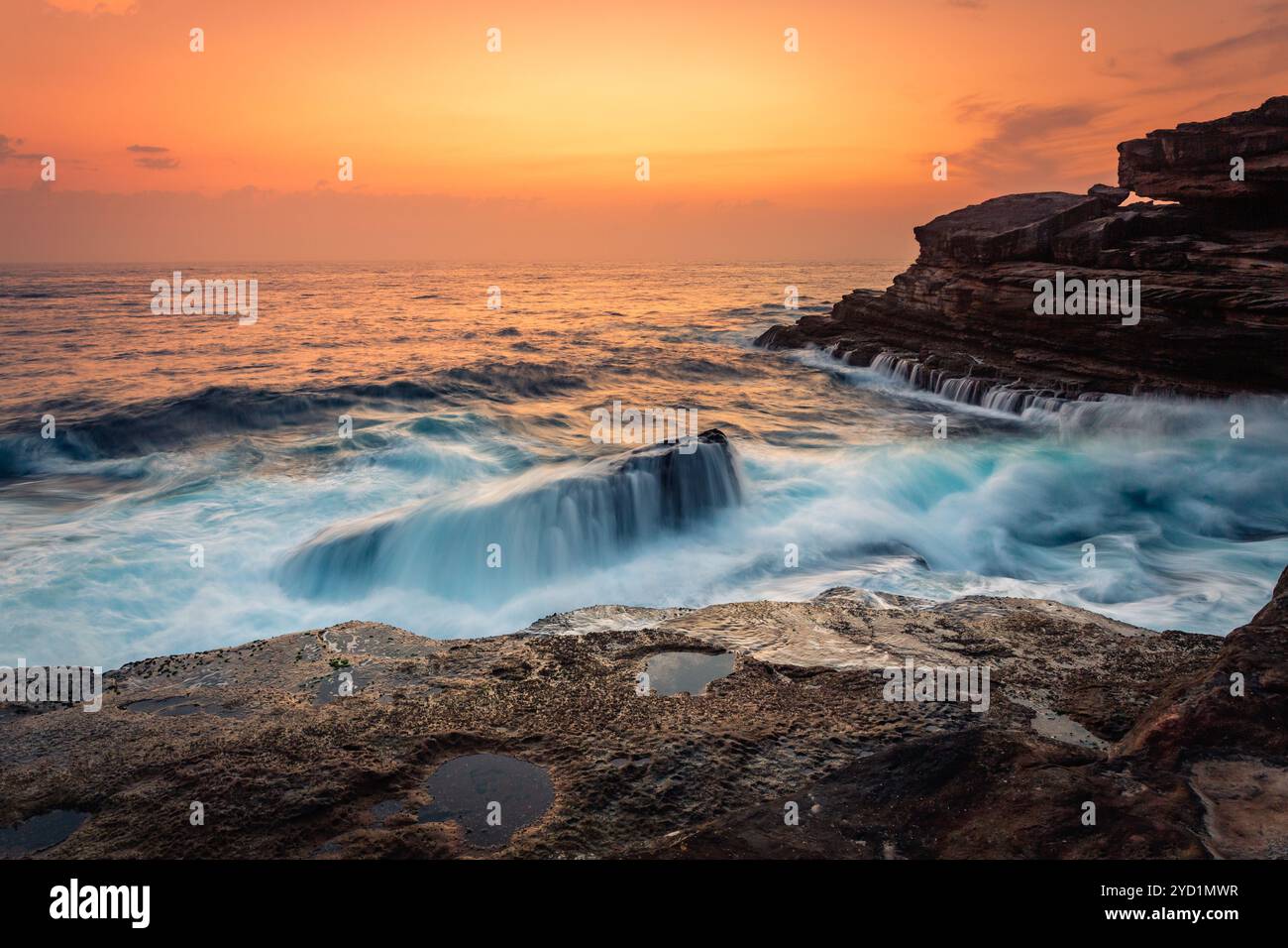 Un lever de soleil époustouflant et des vagues s'écrasent sur les rochers de la côte maritime de Sydney Banque D'Images