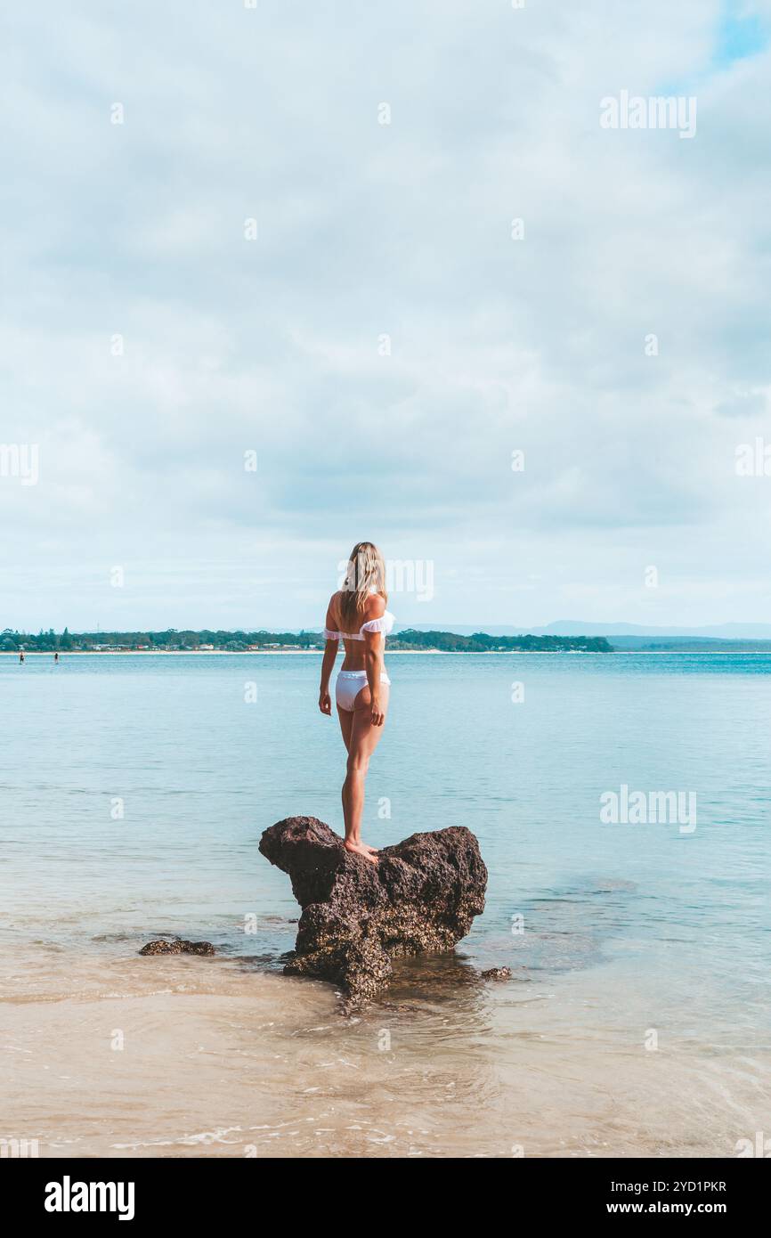 Femme en bikini debout sur un rocher entouré par l'océan Banque D'Images