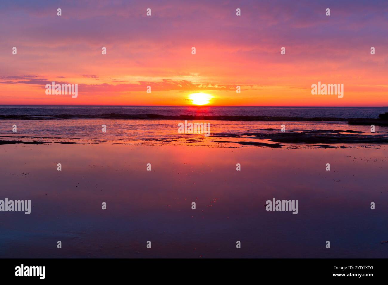 Les levers de soleil côtiers comme les pauses tournent le ciel rouge, orange, rose et jaune Banque D'Images