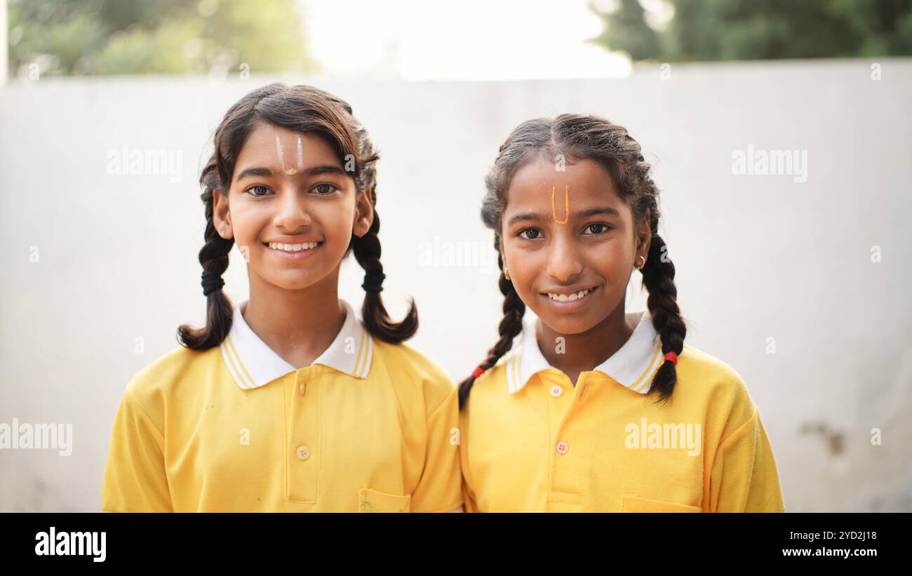 Portrait de joyeux enfant d'école indienne ou des enfants en uniforme levant la main dans la salle de classe tout en étudiant avec des livres et un ordinateur portable. Apprentissage en ligne Banque D'Images